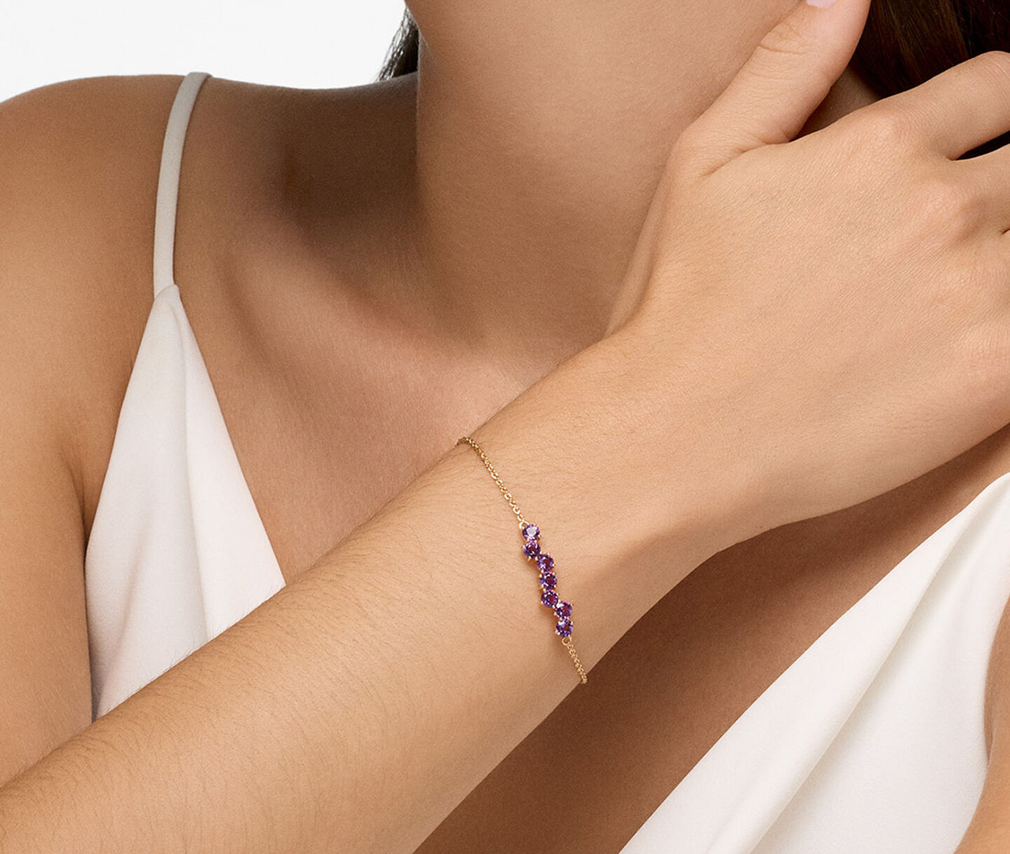 A woman wearing a amethyst and gold bracelet.
